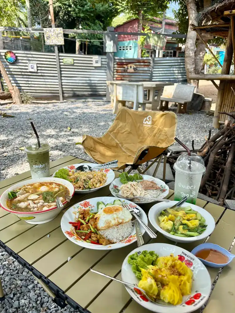 Soup, rice with a fried egg and other dishes on a camp table in the garden by daylight