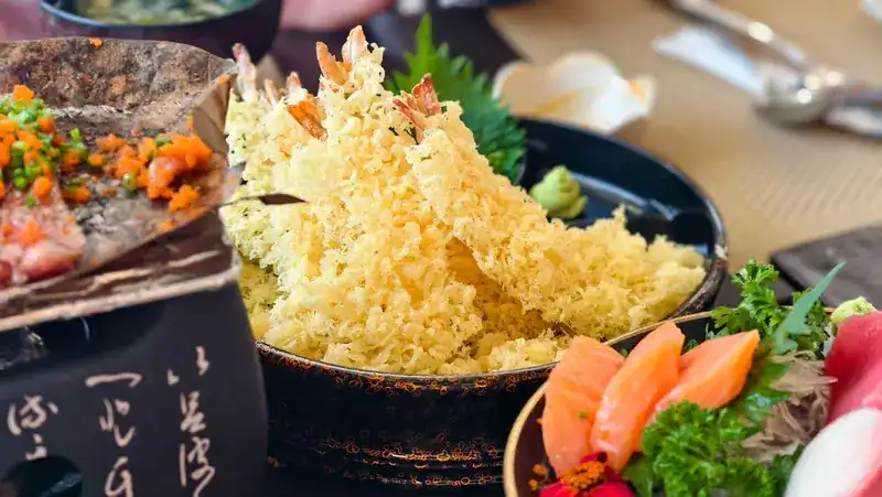 Prawn tempura in a light, lacy batter beside a plate of sashimi