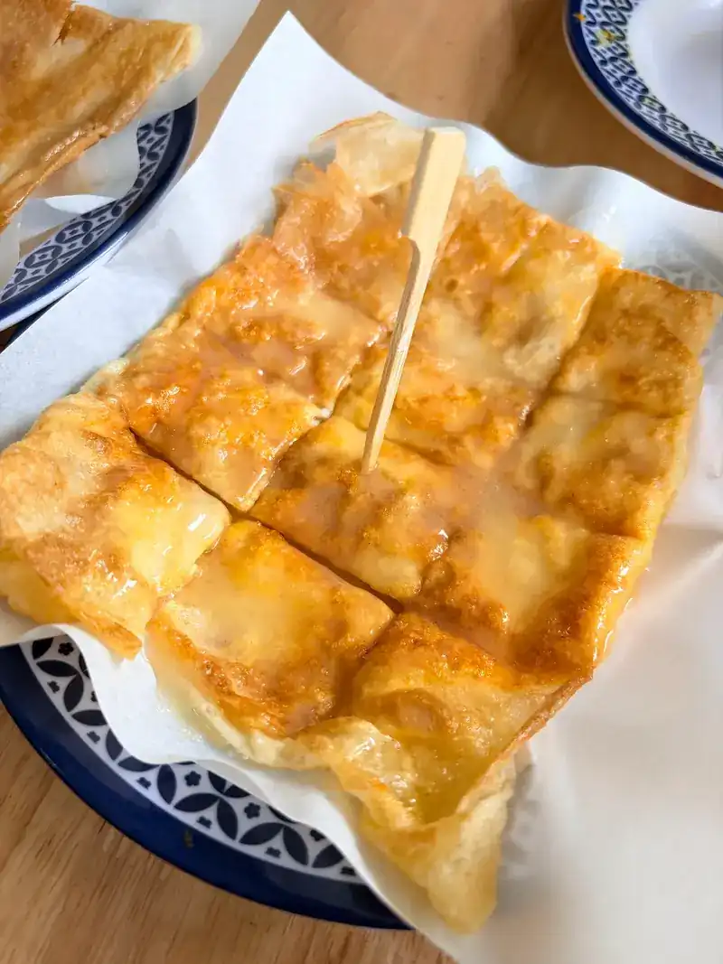 Golden roti cut into squares, with a wooden pick