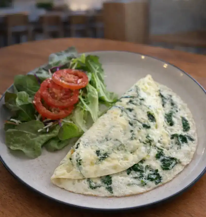 Egg white omelet with spinach beside a tomato and leaf salad