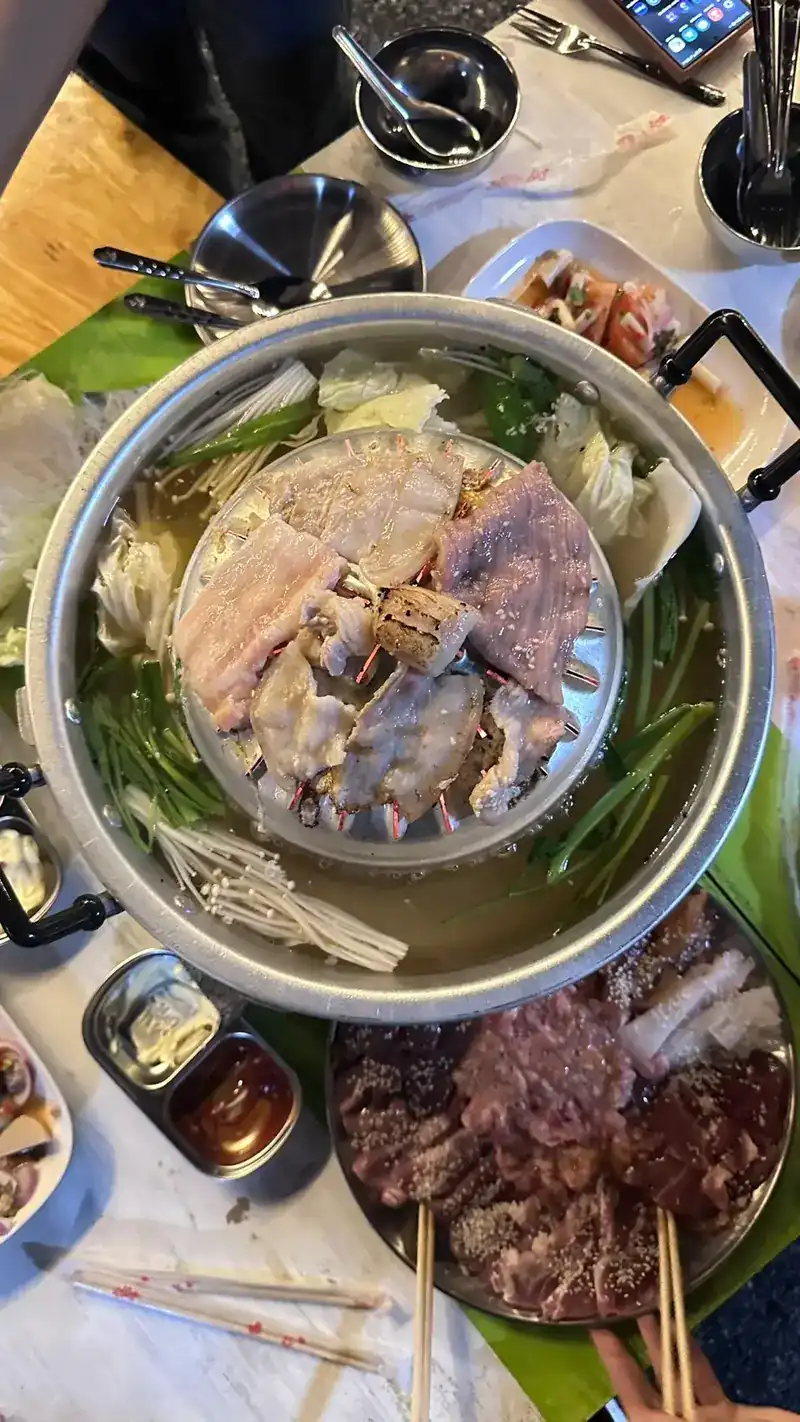 A mookata pan on the table with a plate of beef beside it, seen from above
