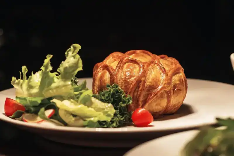A golden pastry-wrapped dish with a fresh salad