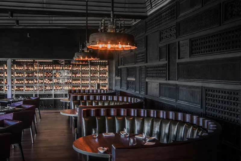 Dining room with leather booths, carved wooden screens and a wall of wine / ห้องอาหารกับโซฟาหนัง ฉากไม้ฉลุ และผนังไวน์