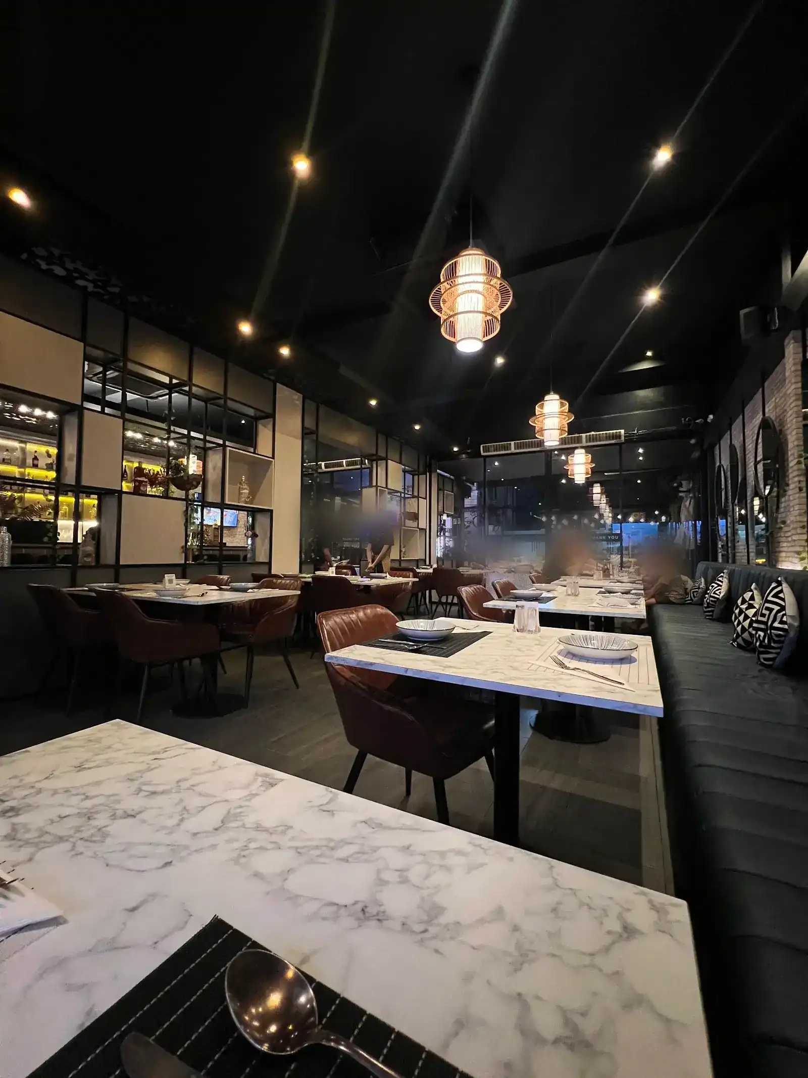 Inside La Piccola: marble tables, brown leather chairs and hanging lanterns under a black ceiling