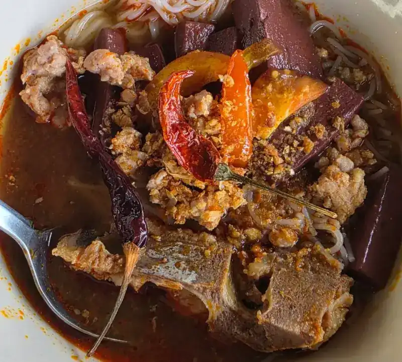Khanom jeen nam ngiao: rice noodles in red broth with minced pork, pork blood and dried chillies