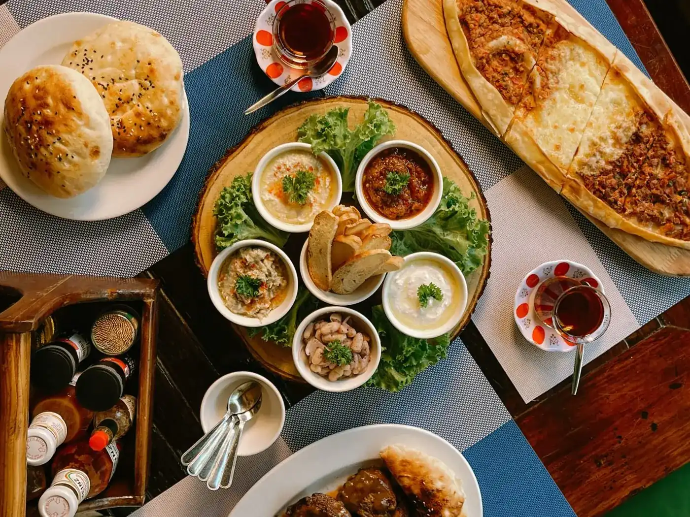 Turkish meze dips, homemade bread, pide and tea on the table, seen from above