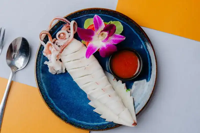 Sliced squid on a blue plate with chilli sauce