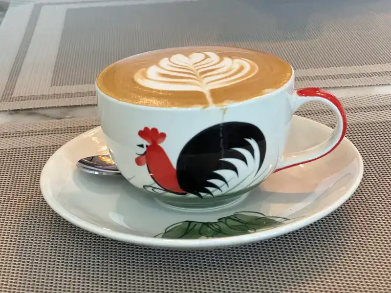 Latte with leaf art in a rooster cup