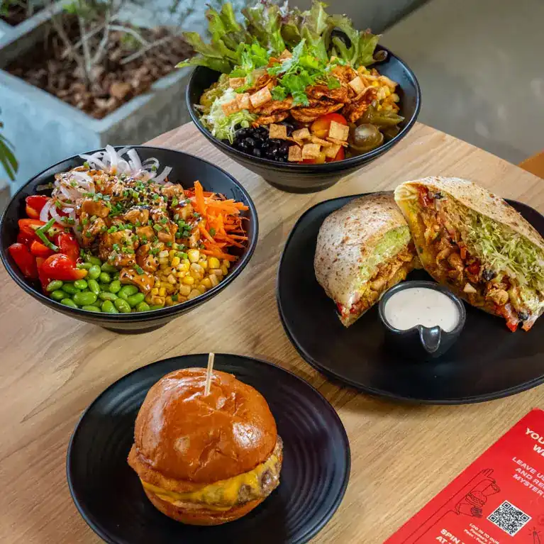 Two bowls and a toasted burrito cut in half on a wooden table