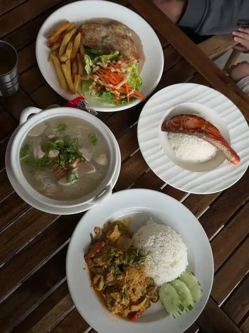 A table of dishes: soup, salmon with rice, a stir-fry with rice and a plate with fries