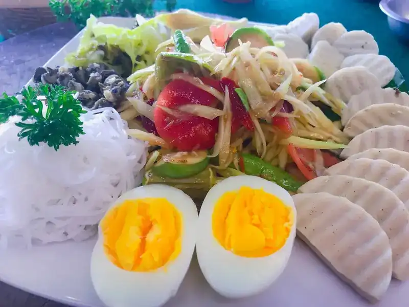 Papaya salad platter with boiled egg, rice noodles and pork sausage