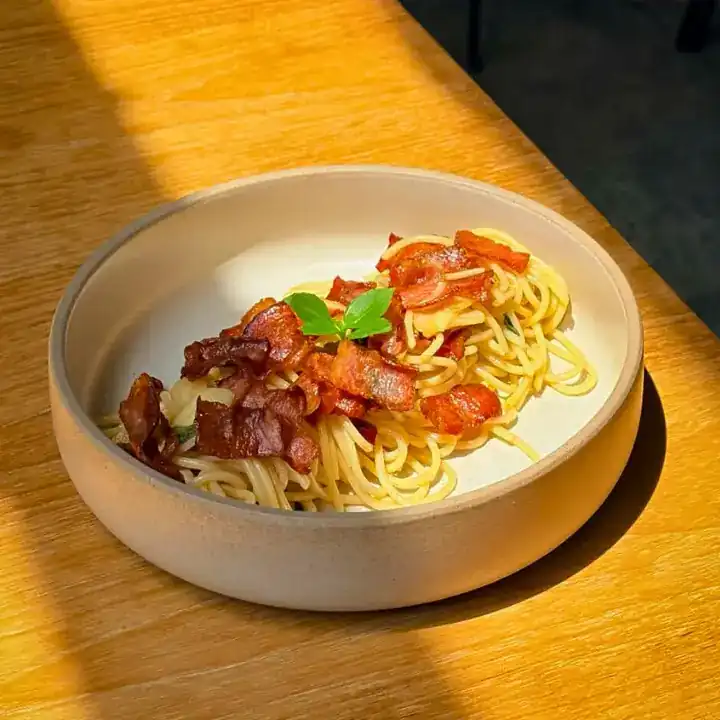 Spaghetti with crispy bacon and basil in a stoneware bowl