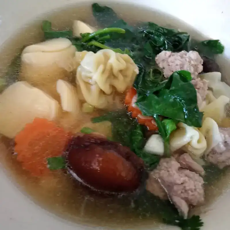 Clear soup with wontons, minced pork, greens, carrot and a shiitake mushroom