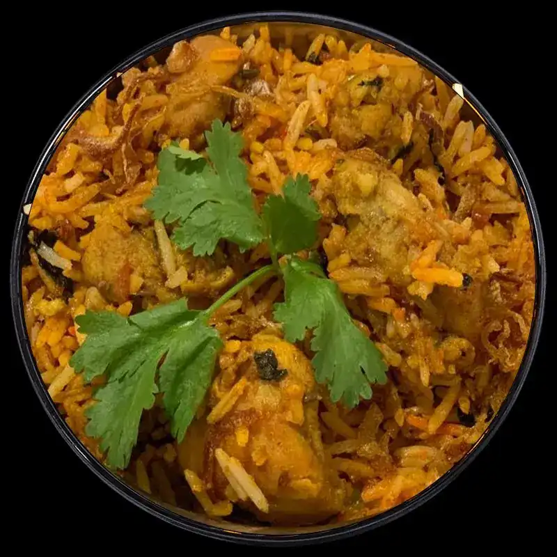 A bowl of chicken biryani topped with fresh coriander