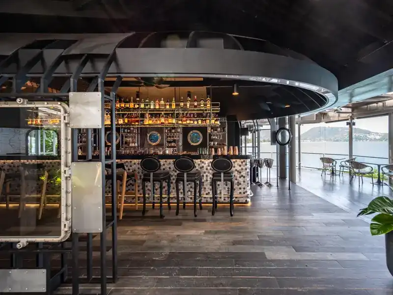 The bar counter with porthole windows and the bay behind