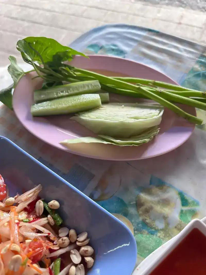 Papaya salad with peanuts, and a plate of cabbage, cucumber and fresh greens
