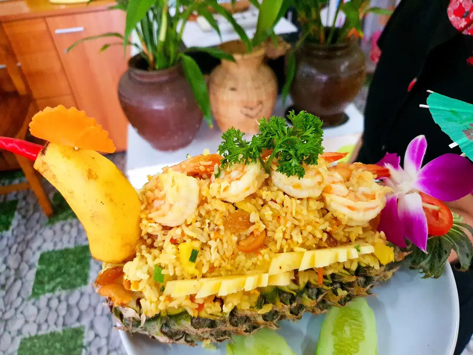 Pineapple fried rice with prawns, served in half a pineapple with a bird carved from a banana and a purple orchid