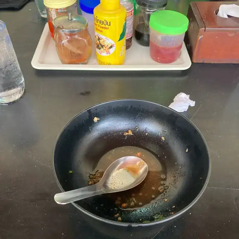 An empty bowl with a spoon, beside a tray of condiments