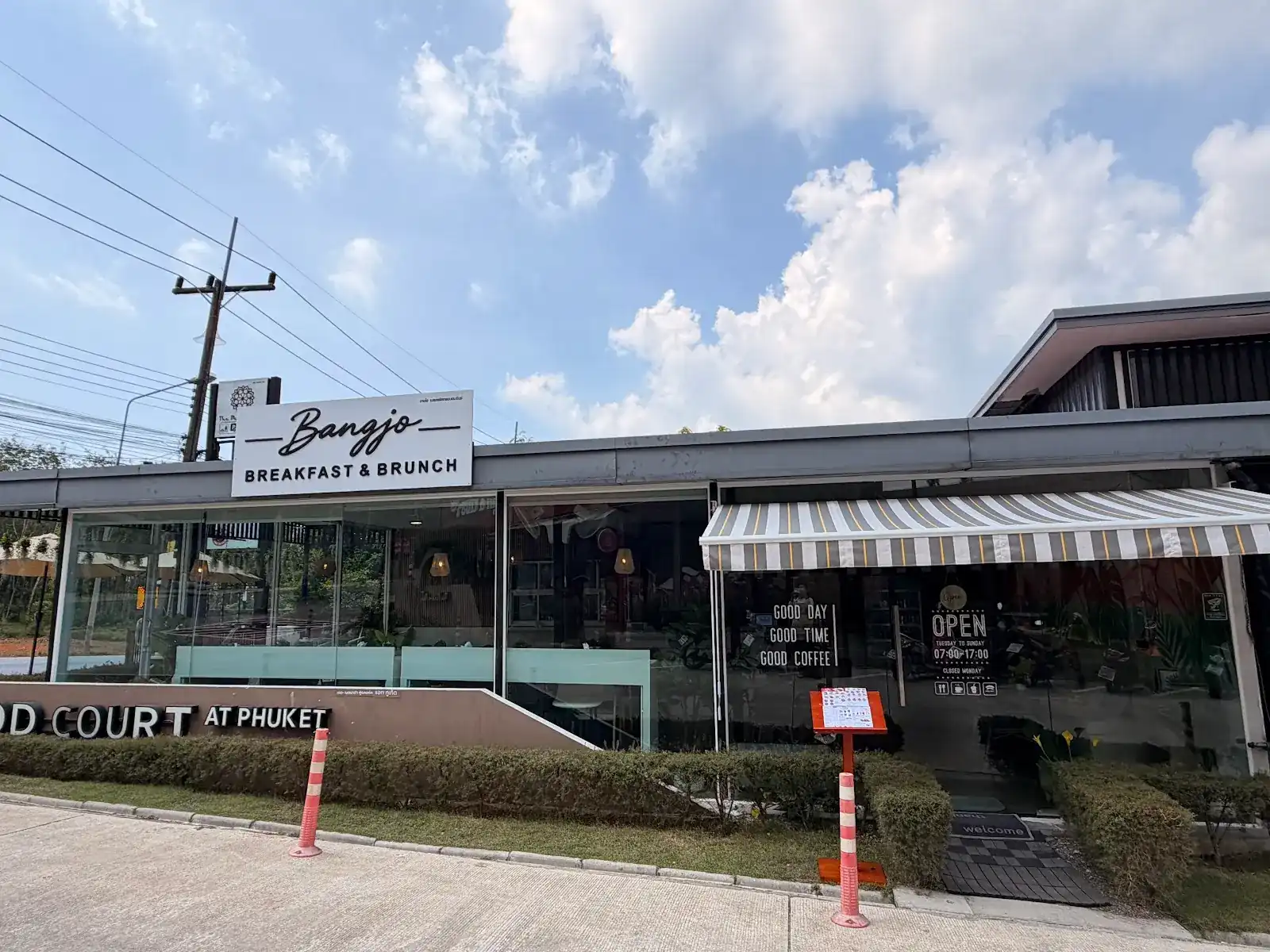 The Bangjo Breakfast & Brunch shopfront in Si Sunthon: the white sign over the glass front and the striped awning over the door