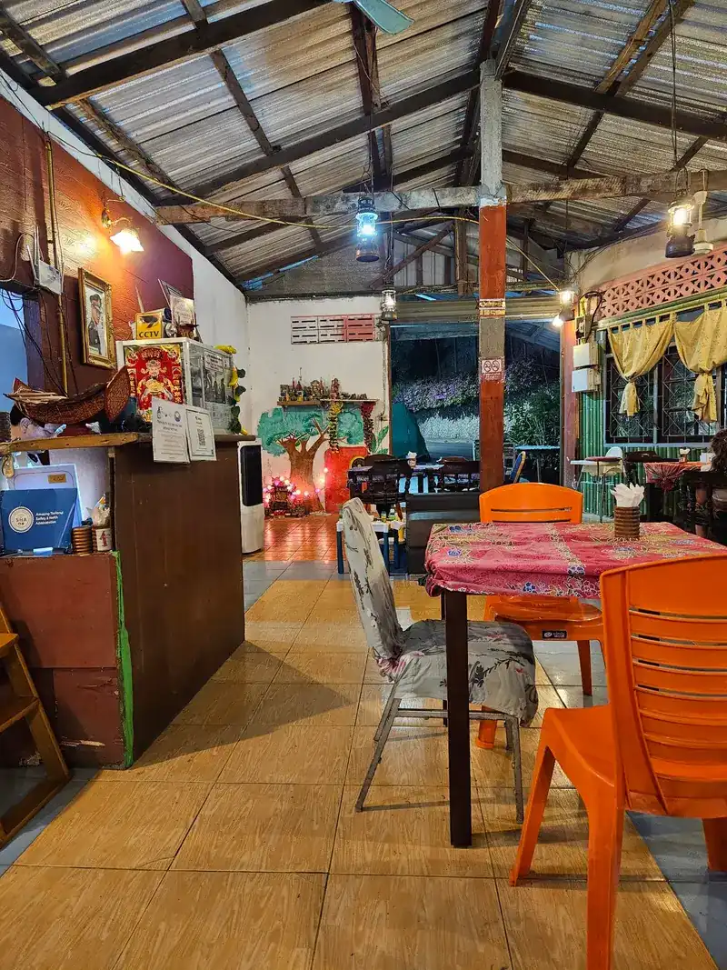 Inside the restaurant: tiled floor, orange chairs and a patterned tablecloth