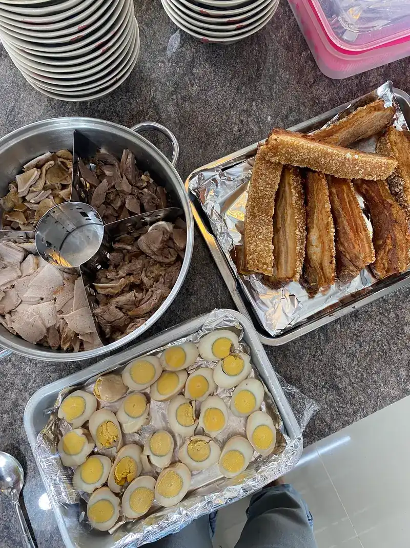 Trays on the counter: sliced pork and offal in a pot, crispy pork belly and halved eggs