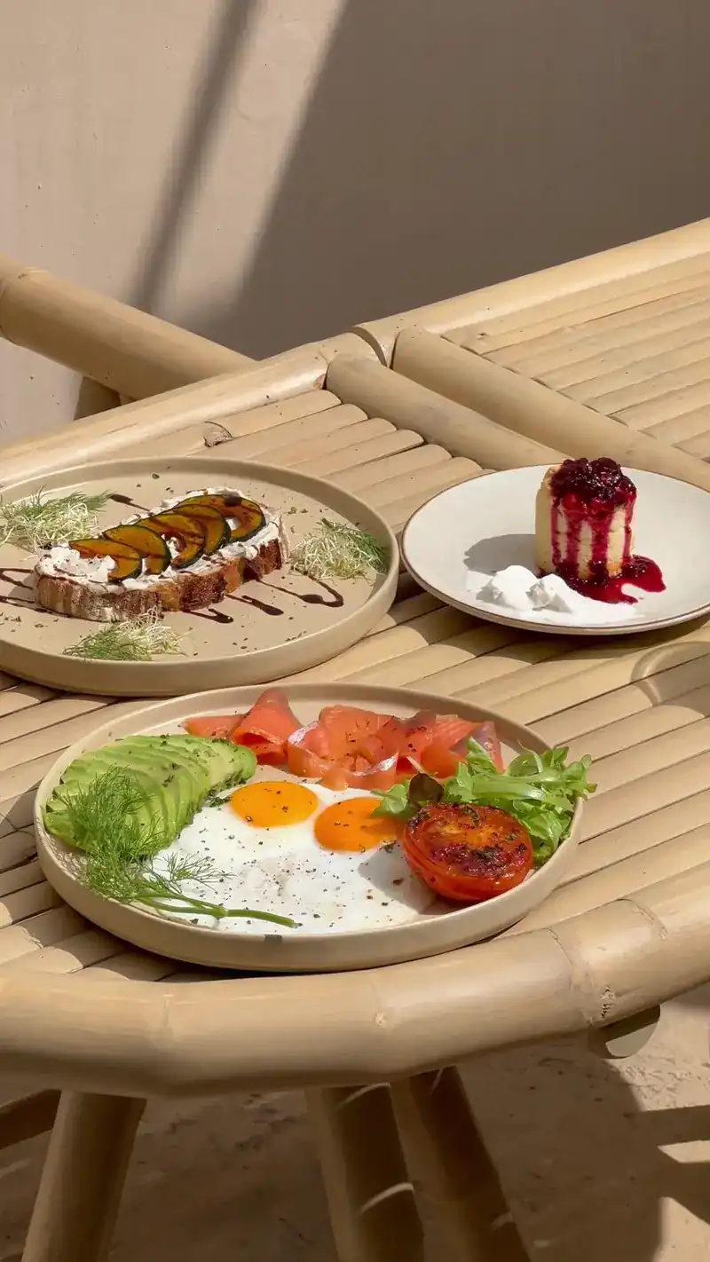 Brunch on bamboo tables: toast, fried eggs with smoked salmon and avocado, and a small dessert