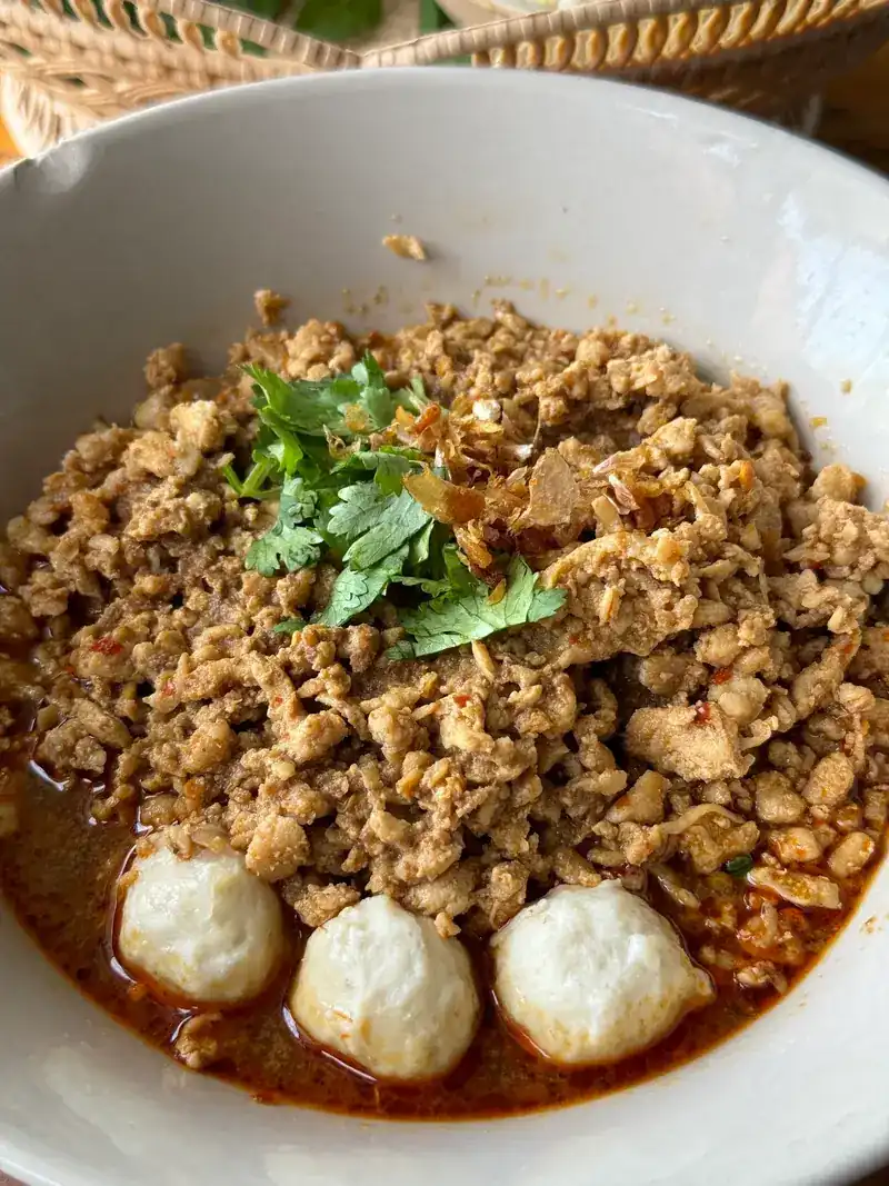 A bowl topped with minced meat, coriander and three meatballs