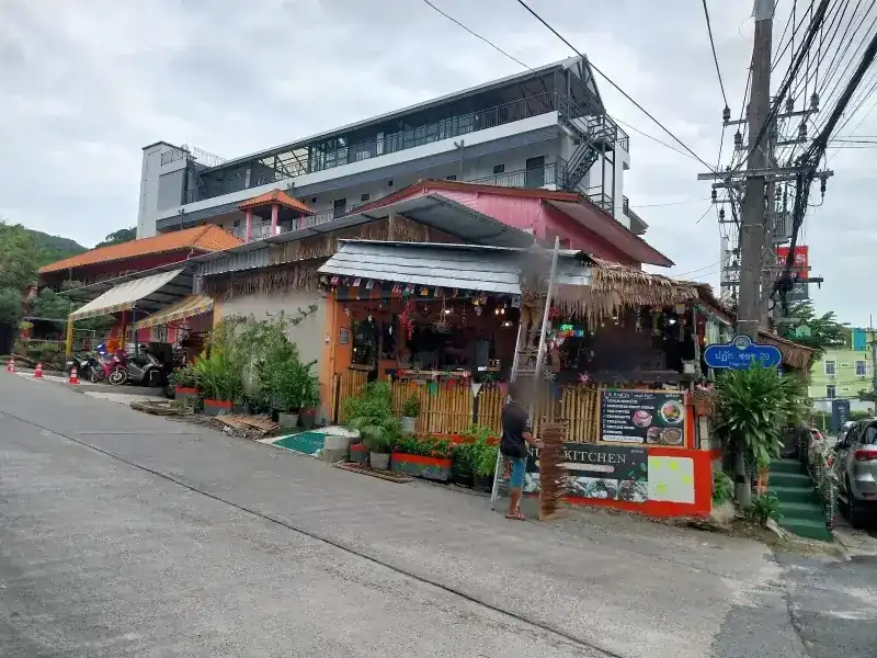 The front of Nui's Kitchen on Patak Soi 20, with plants, a bamboo fence and the street sign at the corner