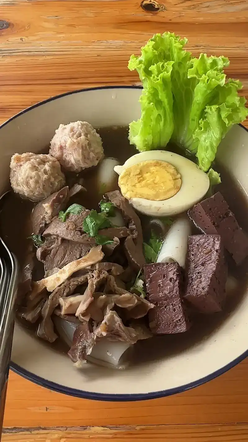 Noodle soup with pork balls, sliced meat, a boiled egg and lettuce