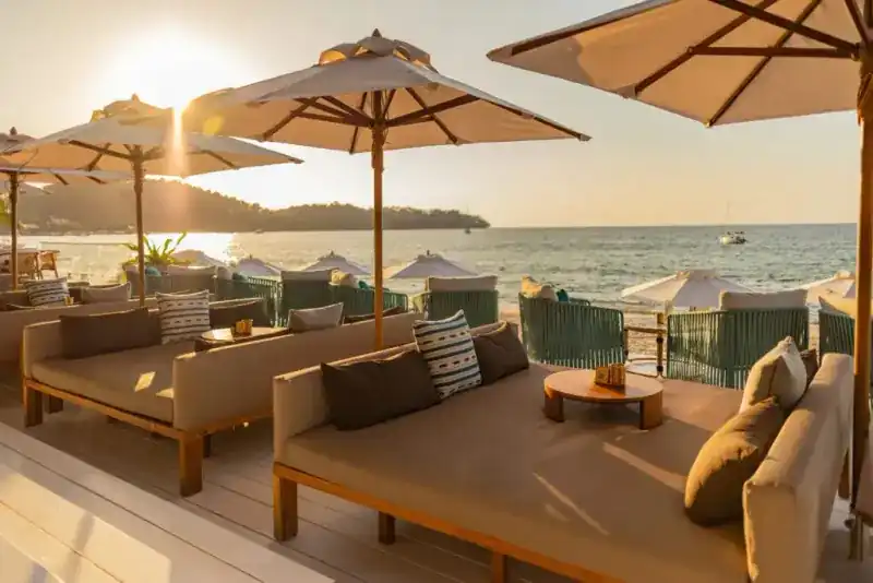 Deep daybeds under parasols as the sun sets over Bang Tao bay