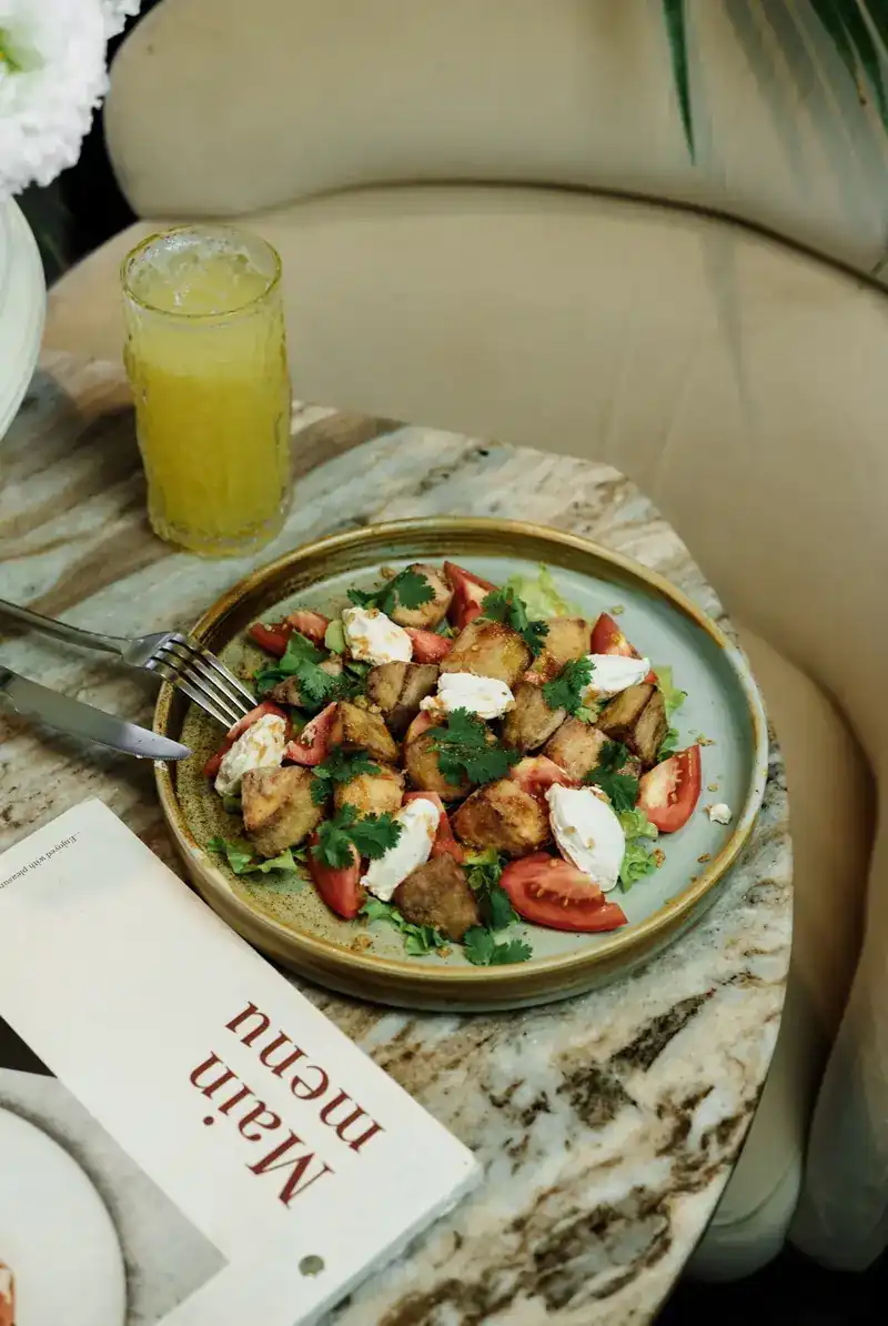 Crispy eggplant salad with tomatoes and burrata on a marble table