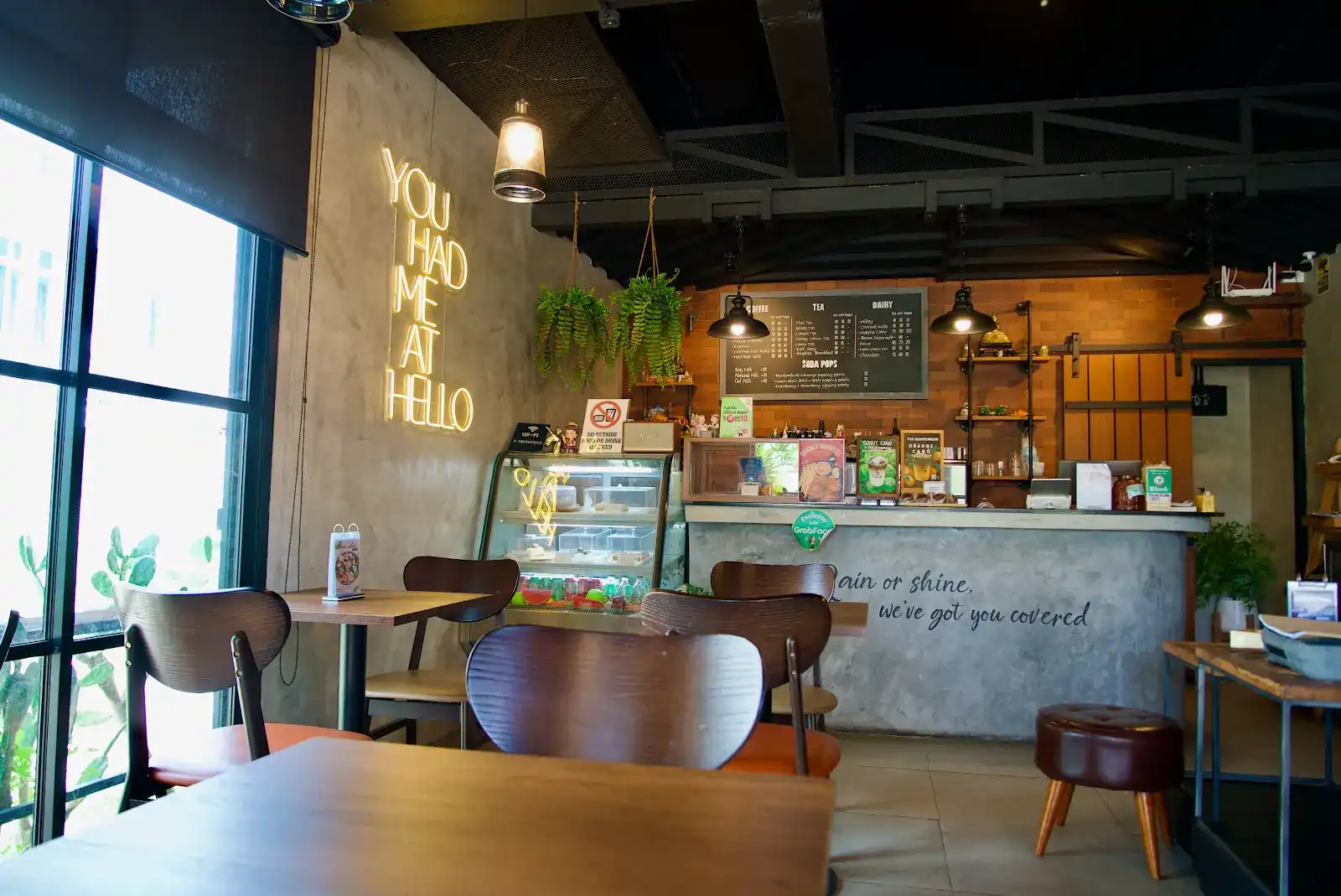 Inside Folk Café: the neon 'You had me at hello' by the window, wooden tables and the concrete counter