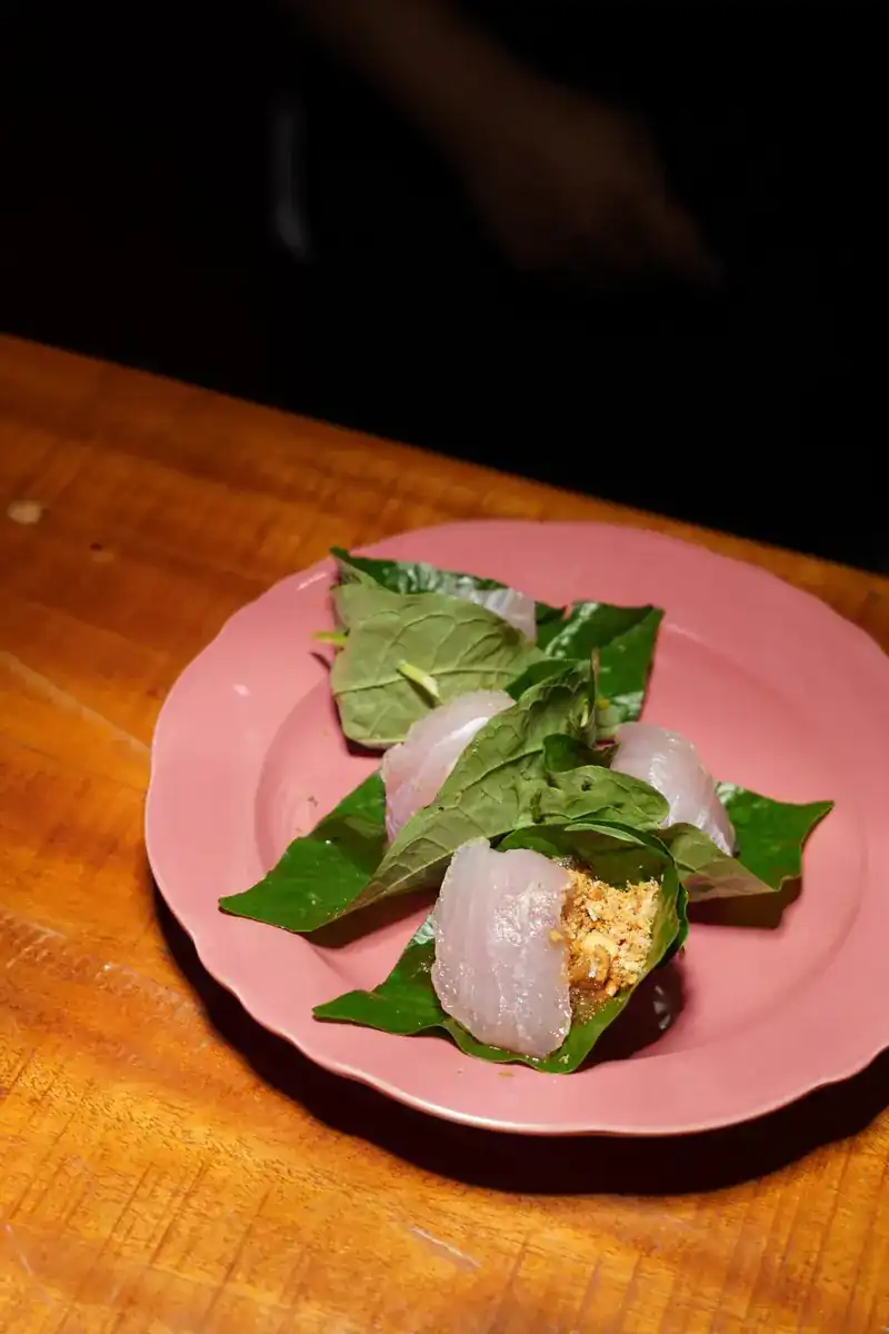 A starter wrapped in green leaves on a pink plate