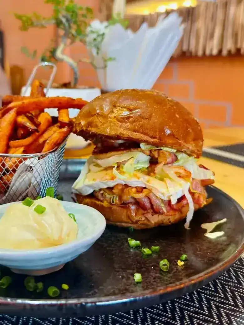 A burger with sweet potato fries and a dip
