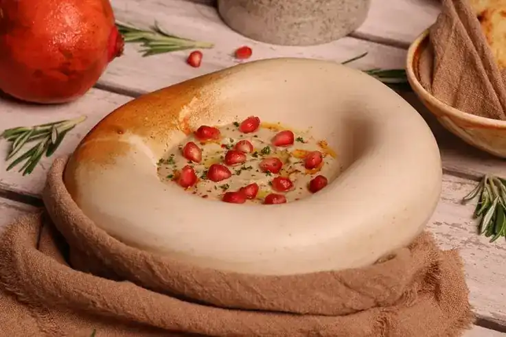 A Mediterranean dip scattered with pomegranate seeds, in a stoneware bowl