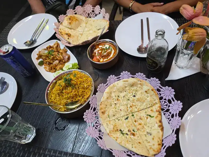 A table set with naan, biryani, a creamy curry and a chicken dish