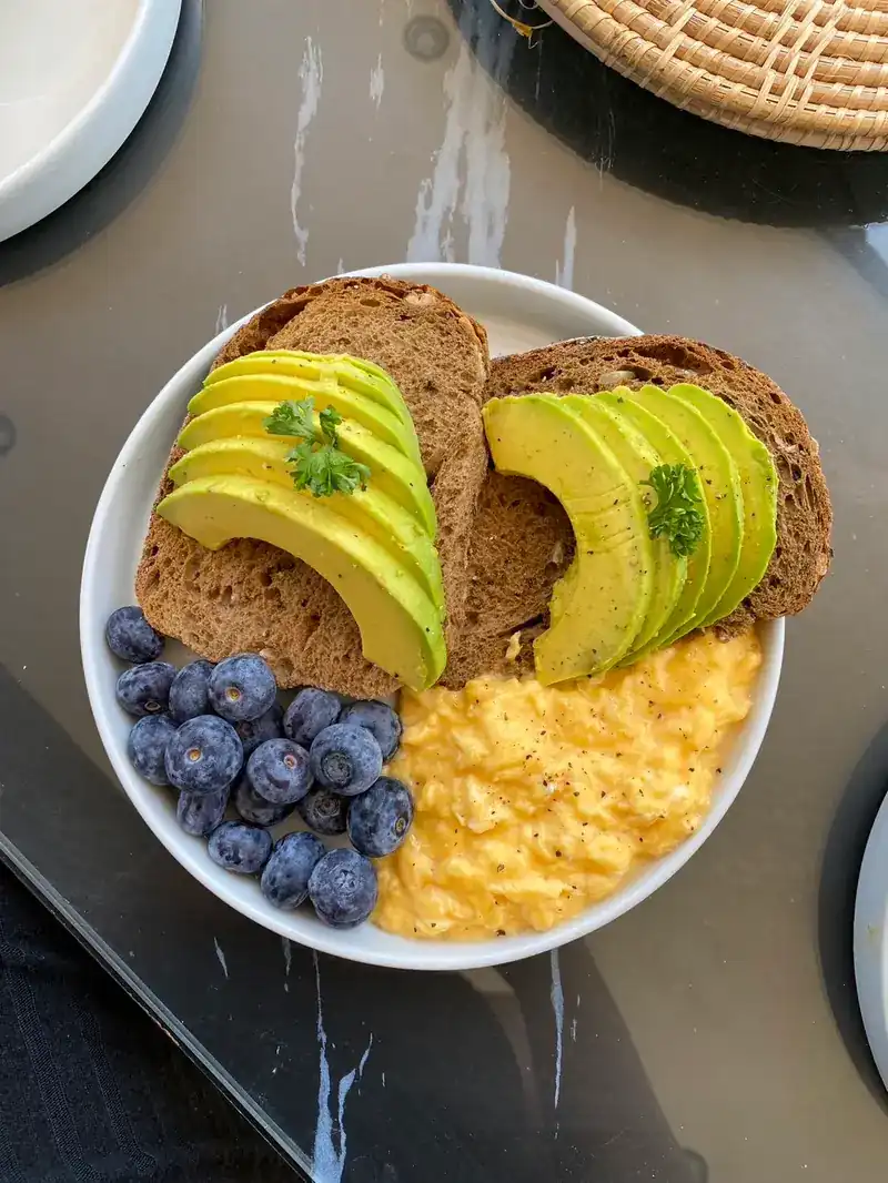 Avocado on wholegrain toast with scrambled eggs and blueberries