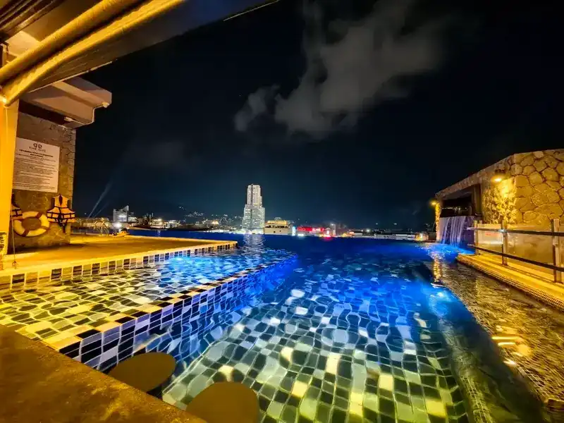The rooftop pool lit blue at night, with the lights of Patong on the horizon