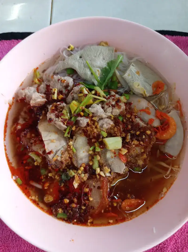 A noodle soup in a red broth with pork and chilli