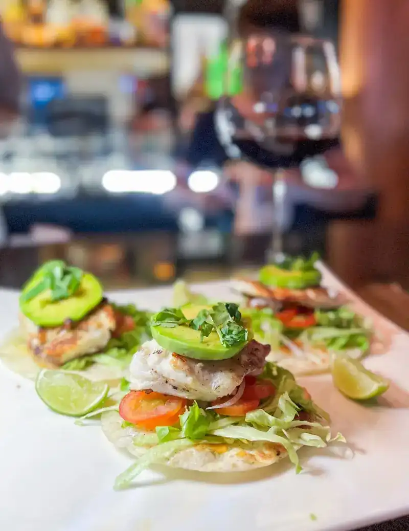 Three small tacos with avocado, tomato, lettuce and lime