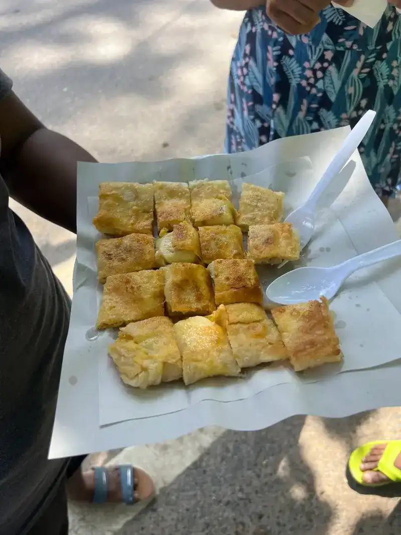 Golden roti cut into squares on paper, with two plastic forks