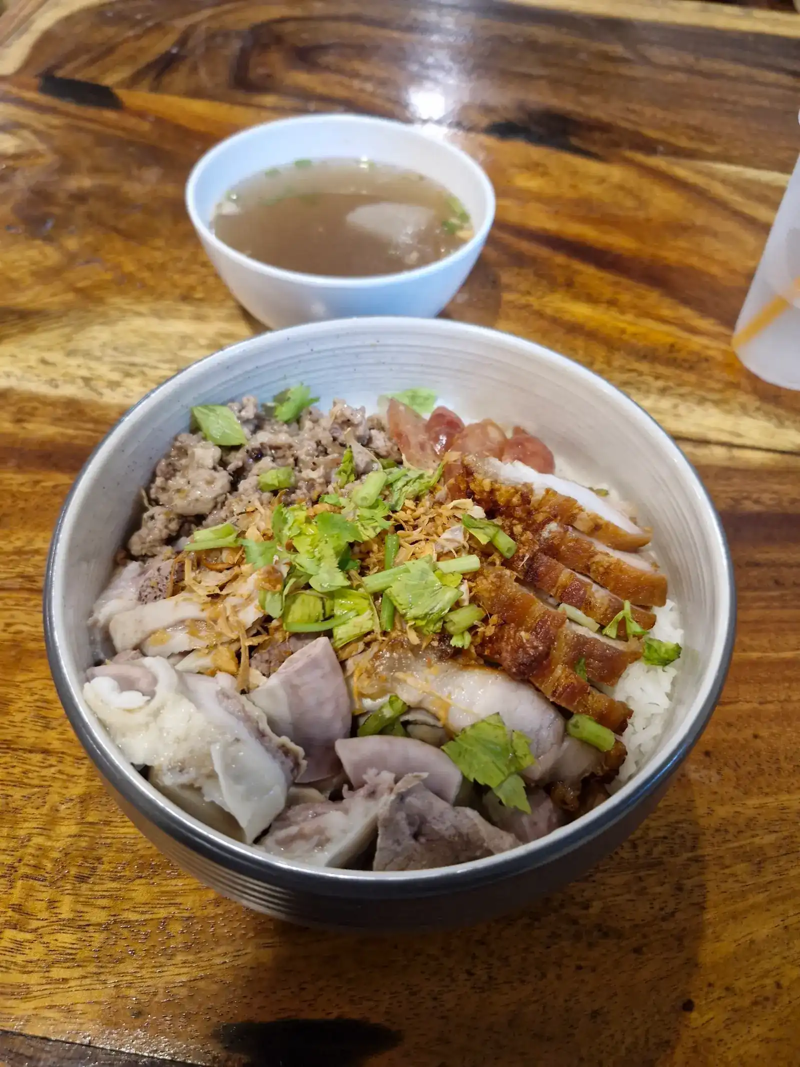 Dry boiled rice: a bowl of rice topped with minced pork, crispy pork, Chinese sausage and sliced pork, with a small bowl of soup behind it