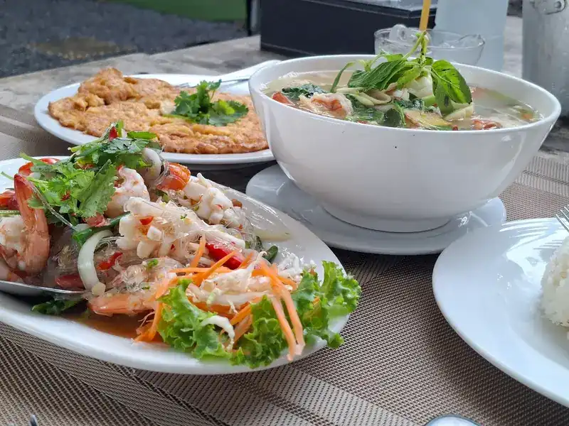 A seafood salad with prawns and squid, a bowl of soup and an omelette on the table