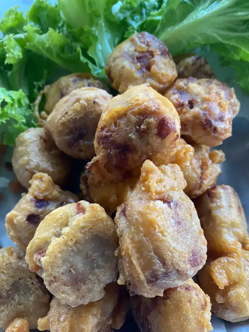 A pile of fried pieces in a light batter on fresh lettuce