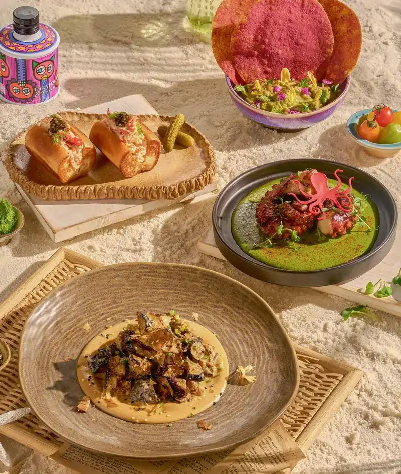 Four dishes set out on white sand in the sun