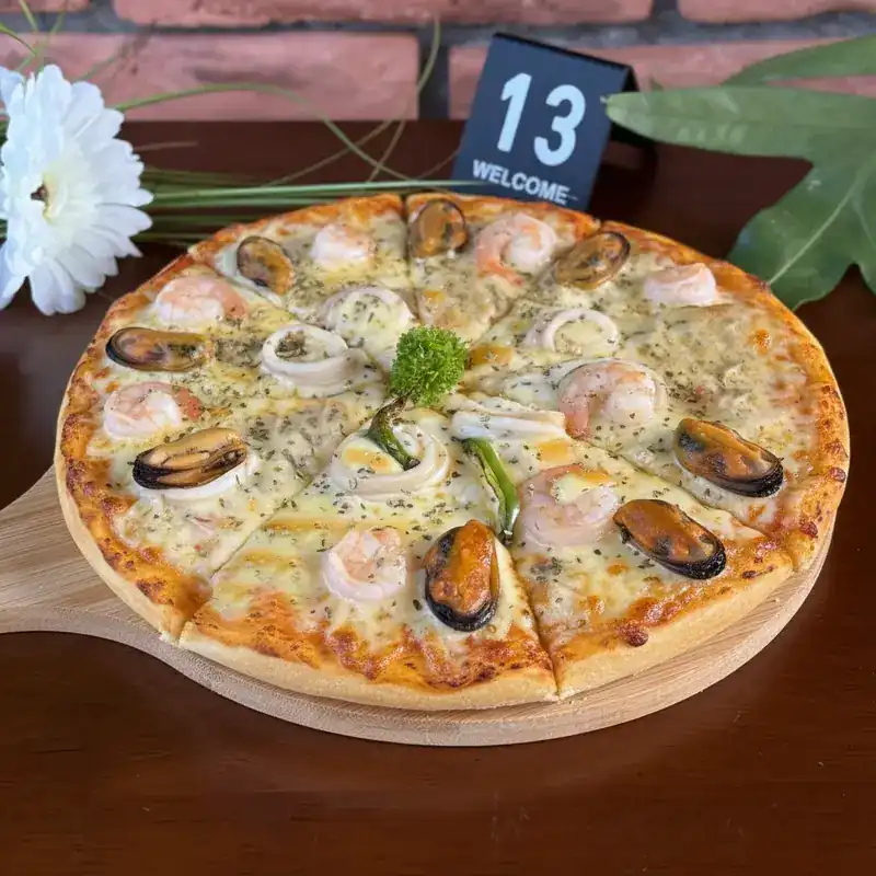 Seafood pizza with prawns, mussels and squid on a wooden board. พิซซ่าซีฟู้ด มีกุ้ง หอยแมลงภู่ และปลาหมึก บนเขียงไม้