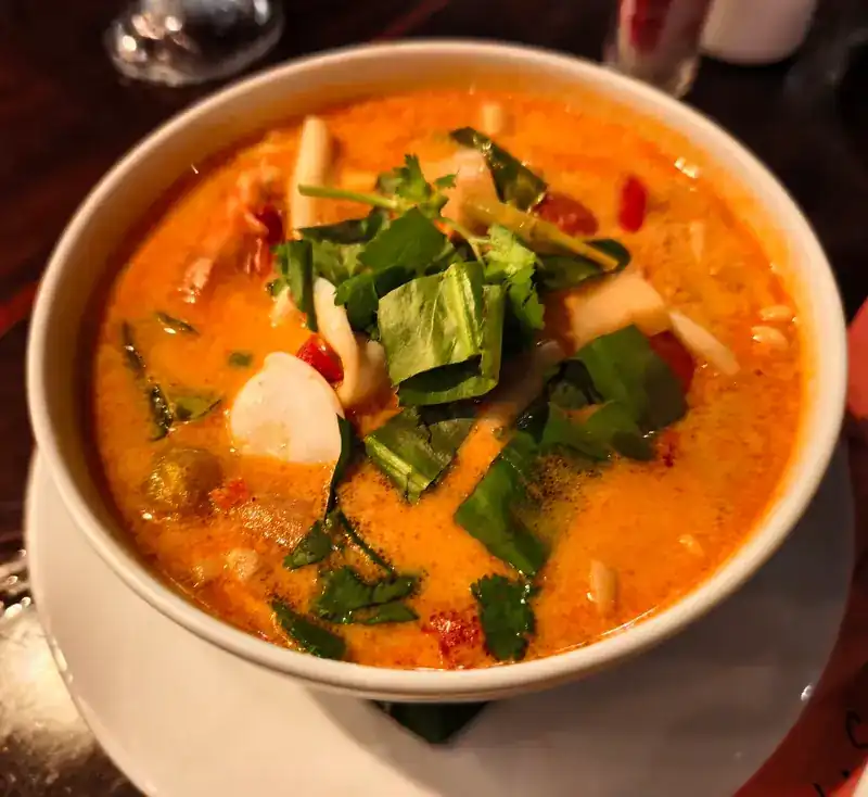 A bowl of spicy Thai soup with fresh herbs and chilli