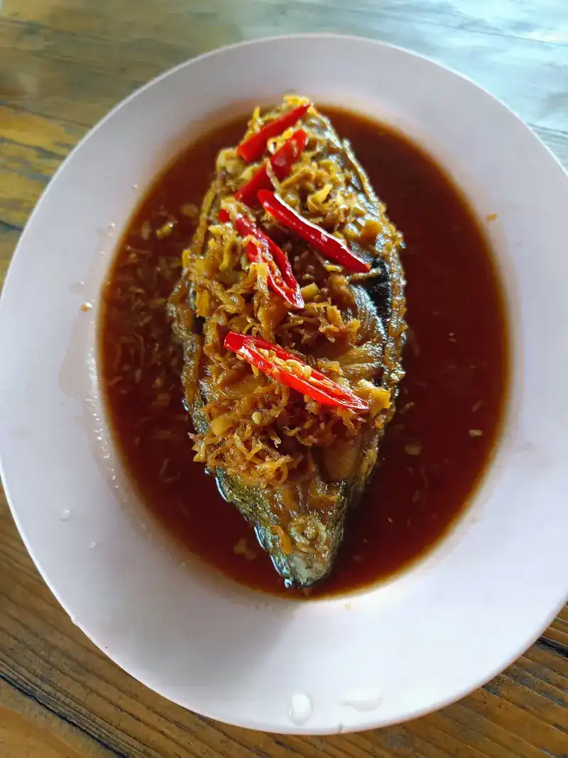 Whole fried fish in a dark sauce, topped with shredded ginger and red chilli