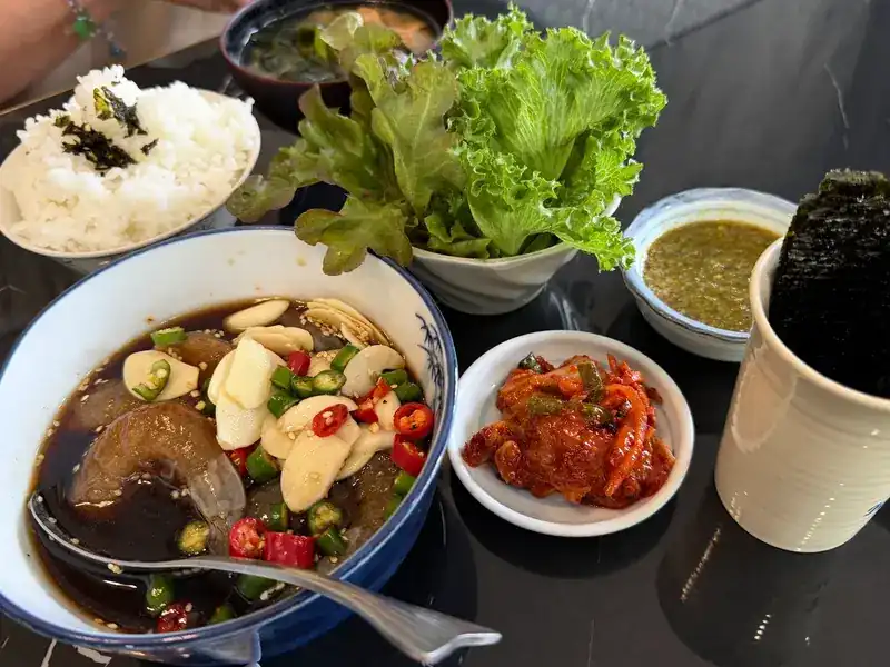 Raw shrimp in soy marinade with garlic and chilli, served with rice, lettuce, kimchi, nori and a green dipping sauce