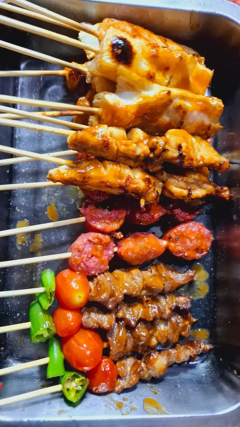 Glazed grilled skewers of chicken, sausage and beef with tomato and green chilli